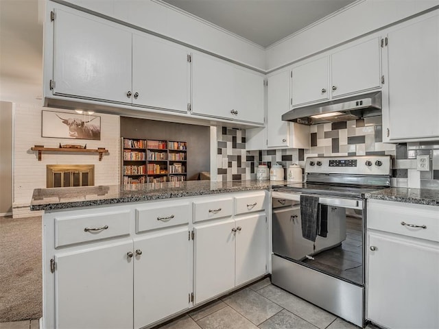 kitchen featuring dark stone counters, kitchen peninsula, stainless steel electric range oven, light tile patterned flooring, and white cabinetry