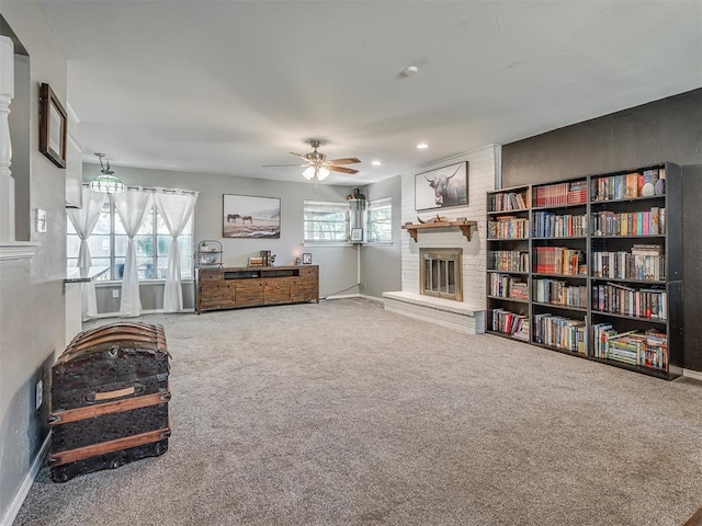 living area featuring carpet floors, a brick fireplace, and ceiling fan