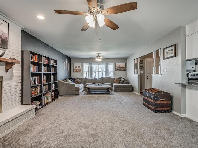 living room featuring carpet flooring, ceiling fan, and a fireplace