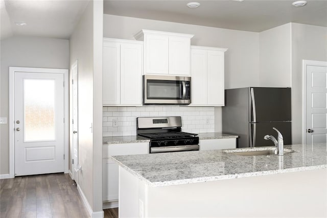 kitchen with sink, tasteful backsplash, light stone counters, white cabinets, and appliances with stainless steel finishes