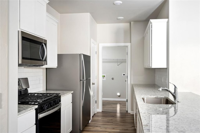 kitchen with light stone counters, sink, white cabinetry, and stainless steel appliances