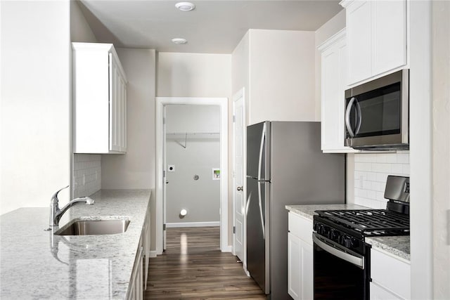 kitchen featuring light stone counters, black range with gas stovetop, white cabinetry, and sink