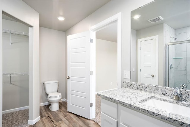 bathroom featuring toilet, vanity, a shower with shower door, and hardwood / wood-style flooring