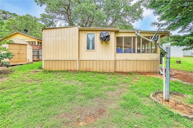 exterior space with a lawn, a sunroom, and a shed