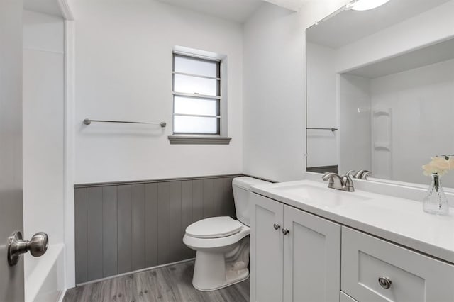 bathroom with hardwood / wood-style floors, vanity, toilet, and wood walls