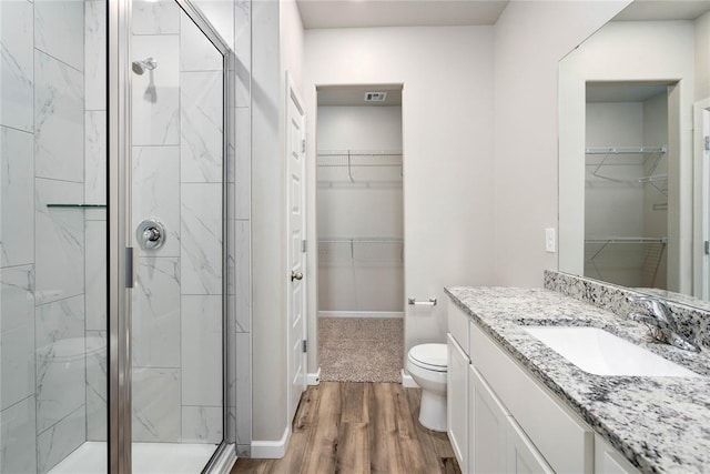 bathroom with hardwood / wood-style flooring, vanity, toilet, and a shower with door