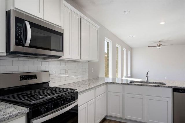 kitchen featuring kitchen peninsula, appliances with stainless steel finishes, white cabinetry, and sink