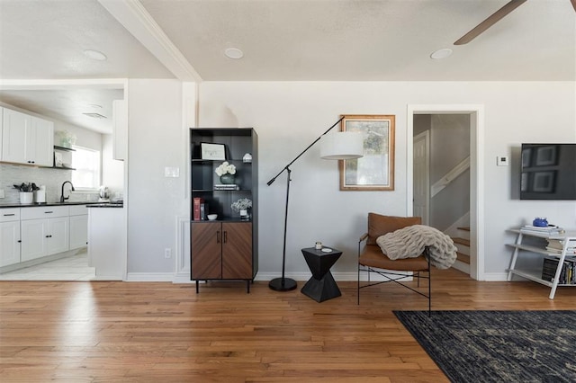 sitting room with ceiling fan, sink, and light wood-type flooring