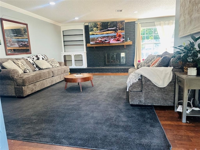 living room featuring built in shelves, a brick fireplace, dark hardwood / wood-style flooring, crown molding, and a textured ceiling