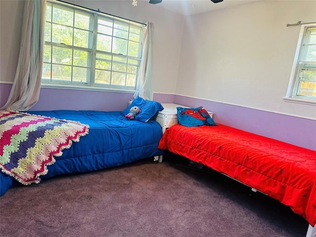 carpeted bedroom featuring multiple windows and ceiling fan