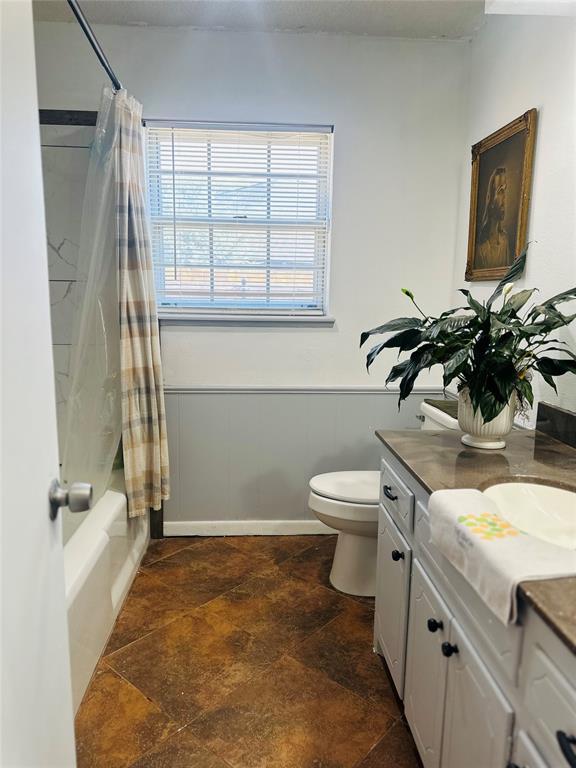 full bathroom with vanity, shower / bath combo, and toilet