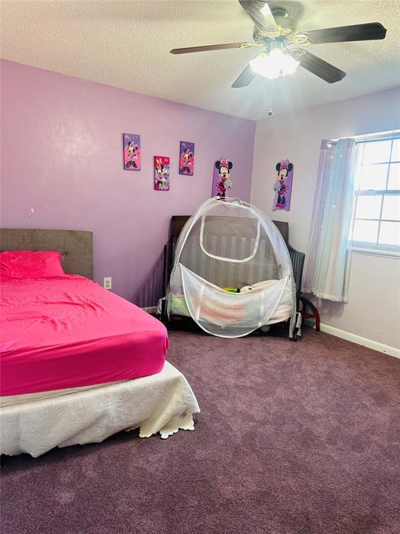 carpeted bedroom with ceiling fan and a textured ceiling