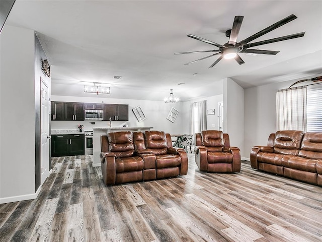 living room featuring ceiling fan with notable chandelier and hardwood / wood-style flooring