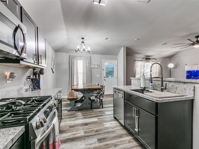 kitchen featuring stainless steel appliances, a kitchen island with sink, pendant lighting, light hardwood / wood-style floors, and lofted ceiling