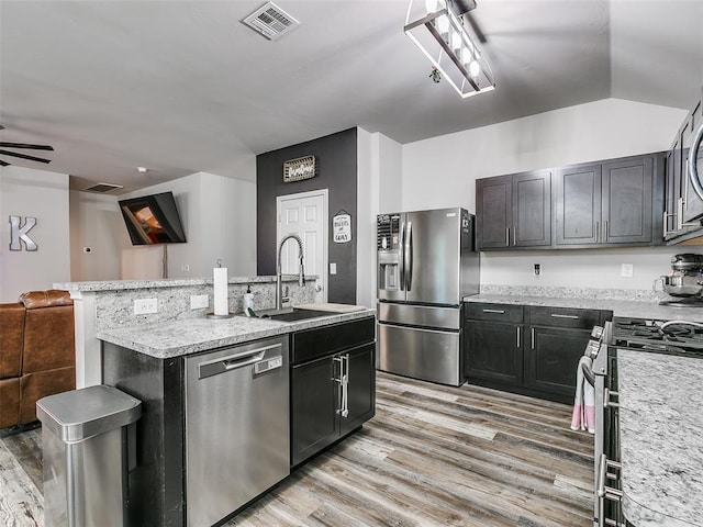 kitchen featuring sink, light wood-type flooring, stainless steel appliances, and a kitchen island with sink