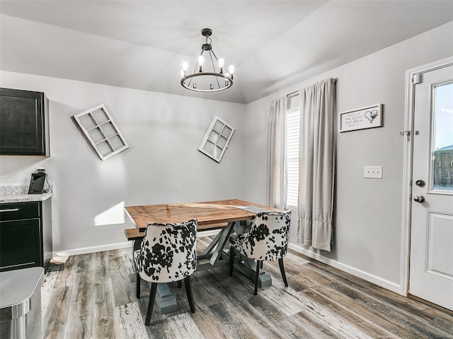 dining area featuring hardwood / wood-style flooring, lofted ceiling, and a notable chandelier