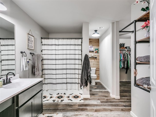 bathroom featuring a shower with shower curtain, wood-type flooring, vanity, and toilet