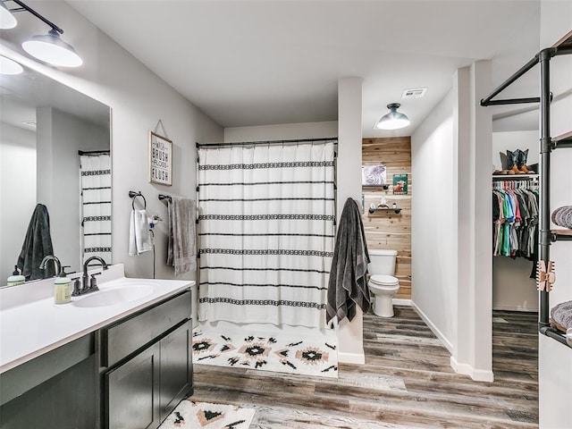 bathroom featuring hardwood / wood-style floors, vanity, wood walls, toilet, and walk in shower