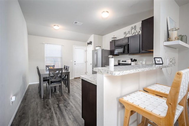 kitchen featuring kitchen peninsula, stainless steel fridge, a kitchen breakfast bar, dark brown cabinetry, and white stove