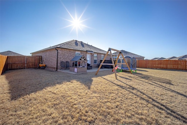 rear view of house featuring a playground, a lawn, and a trampoline