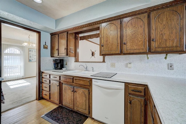 kitchen featuring sink, white dishwasher, tasteful backsplash, light hardwood / wood-style floors, and a chandelier