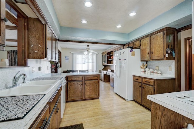 kitchen featuring sink, white appliances, light hardwood / wood-style flooring, backsplash, and kitchen peninsula