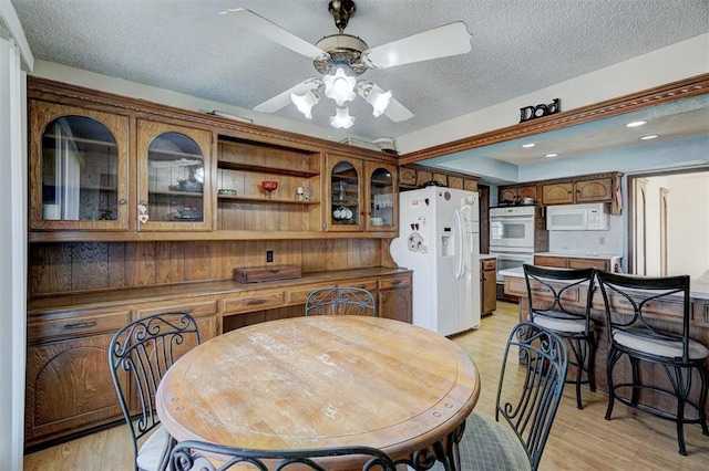 dining room with ceiling fan, light hardwood / wood-style flooring, and a textured ceiling