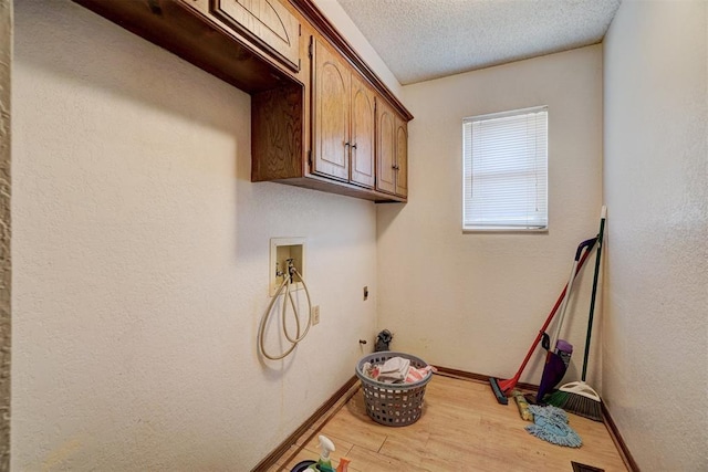 laundry room with cabinets, washer hookup, a textured ceiling, and light wood-type flooring