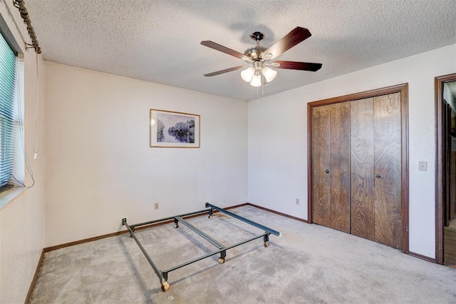 unfurnished bedroom featuring light carpet, ceiling fan, and a textured ceiling