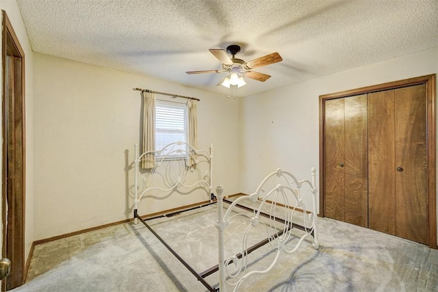 unfurnished bedroom with light carpet, a textured ceiling, ceiling fan, and a closet