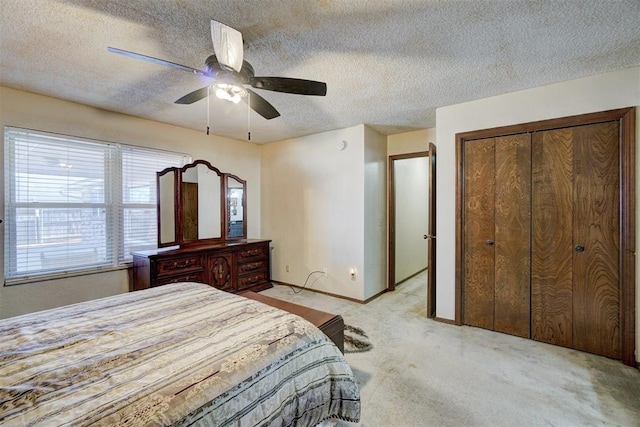 bedroom featuring light carpet, ceiling fan, a closet, and a textured ceiling