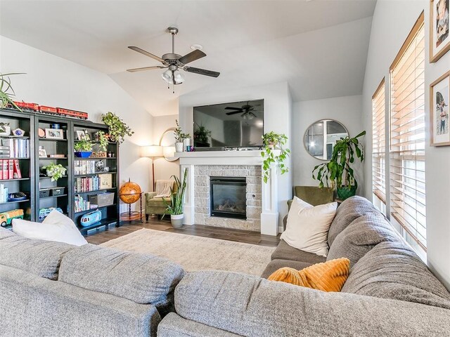 living room featuring dark hardwood / wood-style flooring, a stone fireplace, ceiling fan, and lofted ceiling