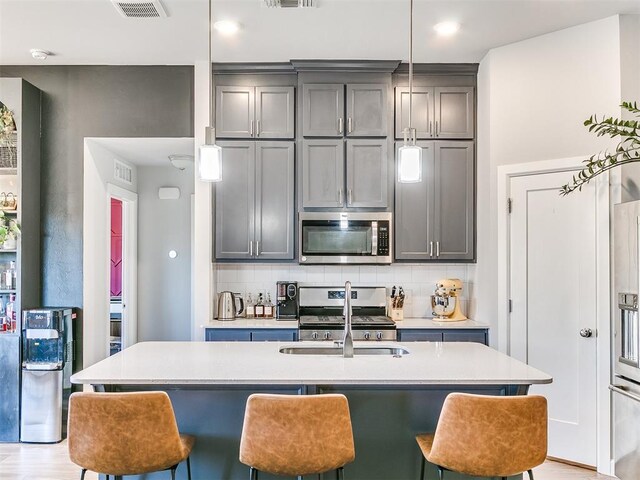 kitchen featuring backsplash, stainless steel appliances, gray cabinetry, and sink