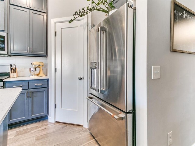 kitchen with light wood-type flooring, backsplash, and high end fridge