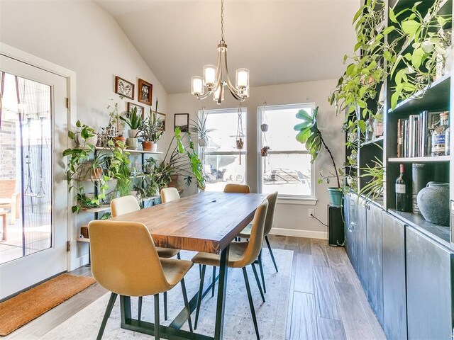 dining space with light hardwood / wood-style flooring, a chandelier, and lofted ceiling