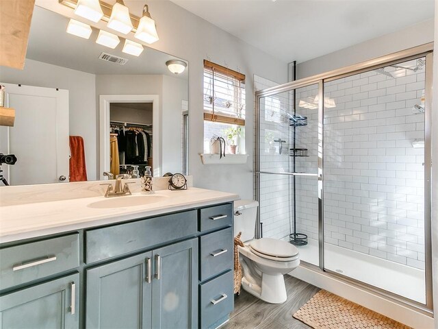 bathroom with hardwood / wood-style flooring, vanity, toilet, and a shower with door