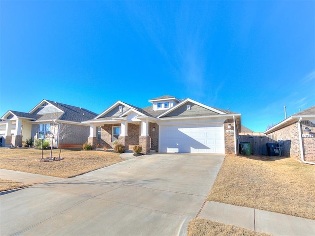 view of front of home with brick siding, driveway, a garage, and fence