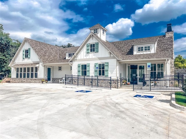 back of property featuring roof with shingles, board and batten siding, a chimney, and fence