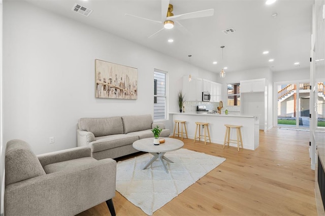 living room with ceiling fan and light hardwood / wood-style flooring