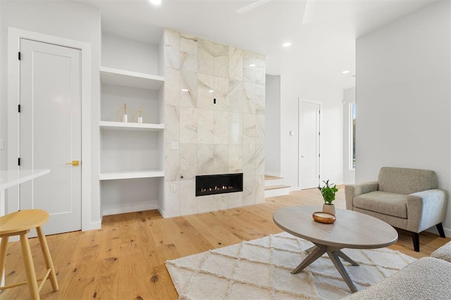 living room featuring light wood-type flooring, built in shelves, and a fireplace