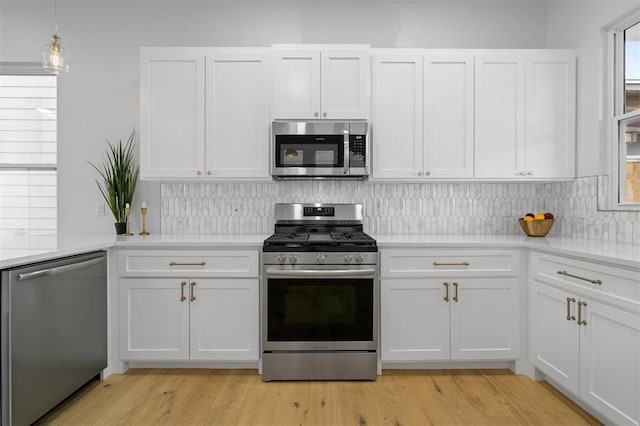 kitchen featuring decorative light fixtures, white cabinetry, stainless steel appliances, and tasteful backsplash