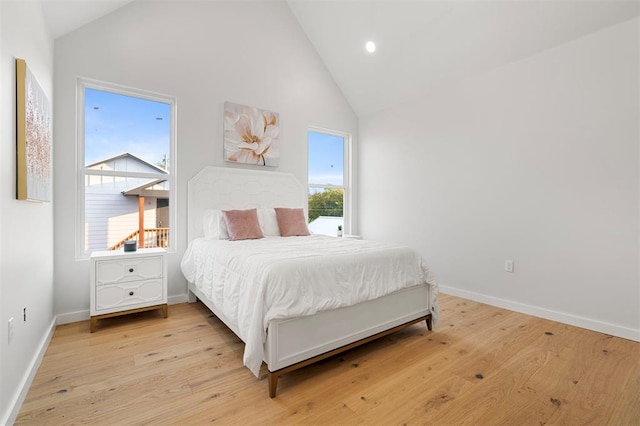 bedroom with light wood-type flooring and high vaulted ceiling