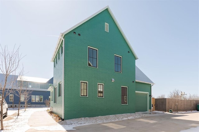 view of home's exterior featuring brick siding, fence, and driveway