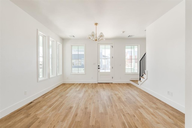 foyer entrance with light wood-style floors, baseboards, stairway, and a chandelier