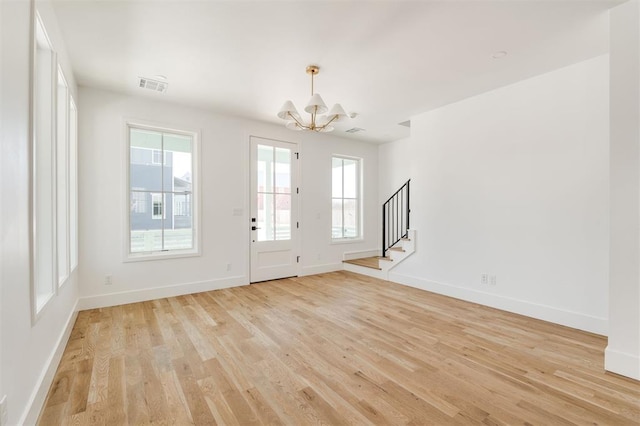 entryway with baseboards, visible vents, stairway, light wood-type flooring, and a notable chandelier