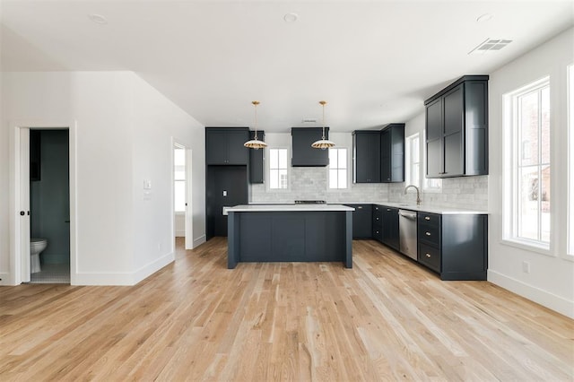 kitchen featuring tasteful backsplash, visible vents, light countertops, light wood-type flooring, and stainless steel dishwasher