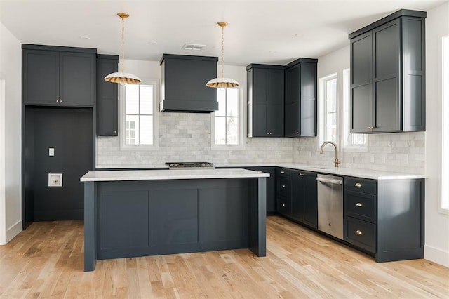 kitchen with light countertops, custom range hood, stainless steel dishwasher, a sink, and light wood-type flooring