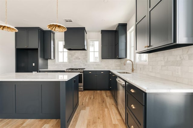 kitchen with light wood finished floors, visible vents, appliances with stainless steel finishes, premium range hood, and a sink