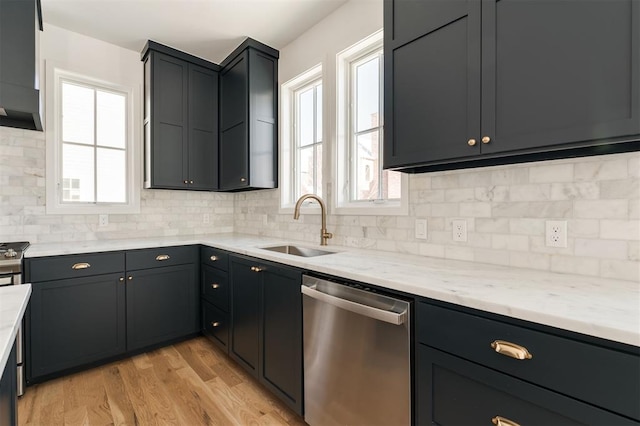 kitchen featuring stainless steel dishwasher, a sink, light wood-style flooring, and a healthy amount of sunlight