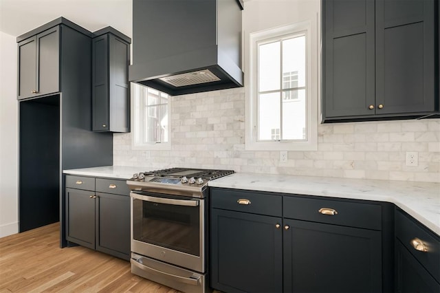 kitchen featuring light wood finished floors, stainless steel gas range oven, custom range hood, and a wealth of natural light